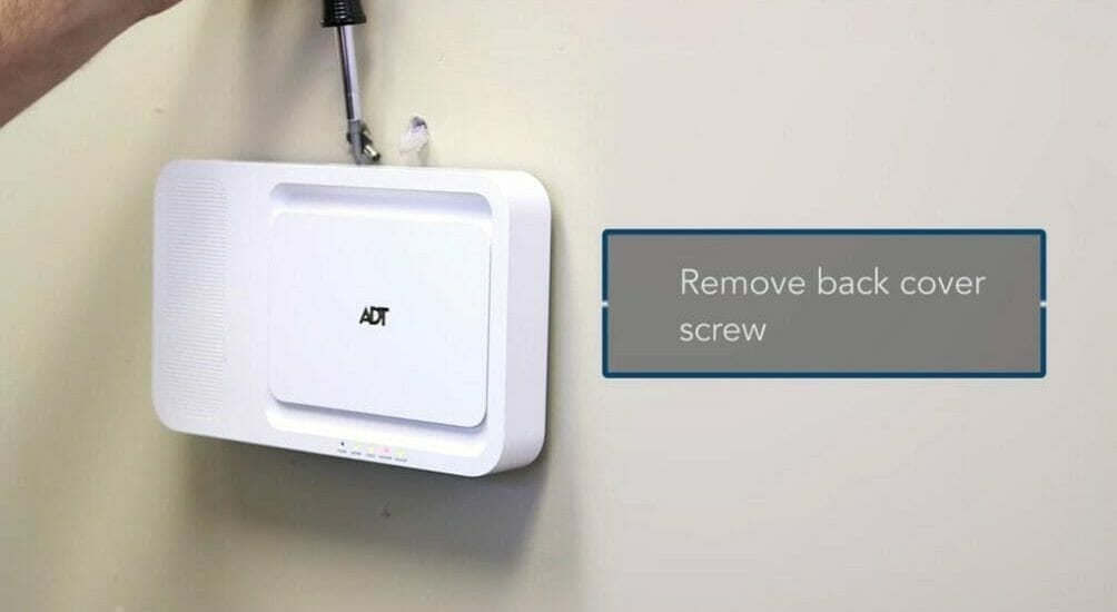 man opening the back cover of ADT device using screw