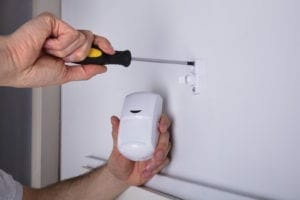 Close-up Of A Young Male Electrician Installing Security System Door Sensor On Wall Close-up Of A Young Male Electrician Installing Security System Door Sensor On Wall