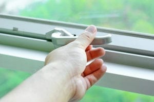 Hand holding glass window latch lever Hand holding glass window latch lever