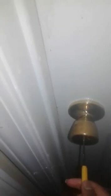 sliding the screwdriver into the doorknob hole