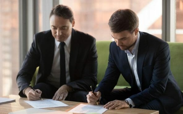 two man signing paper