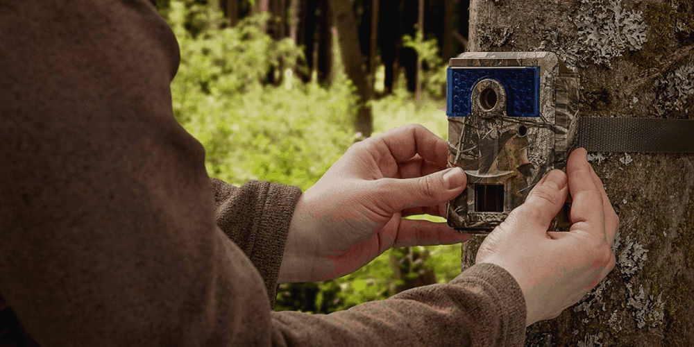 a man placing the trail camera in a tree